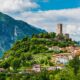 Un panorama del Friuli, in cui si vede un borgo sulle pendici di una collina boscosa sormontata da una torre antica