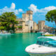 Veduta di Sirmione, Lago di Garda, Lombardia, con una barca in primo piano e il castello sullo sfondo