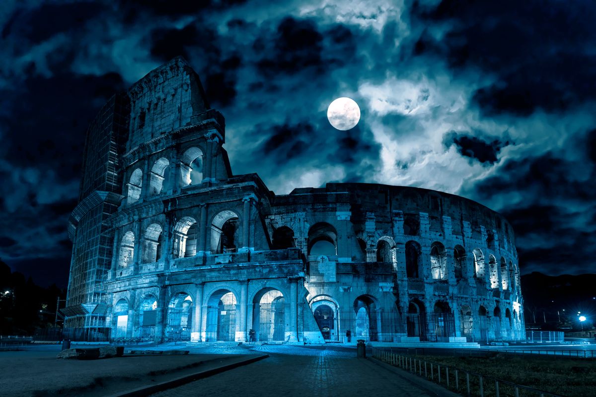 Colosseo di notte con il cielo nuvoloso e la luna