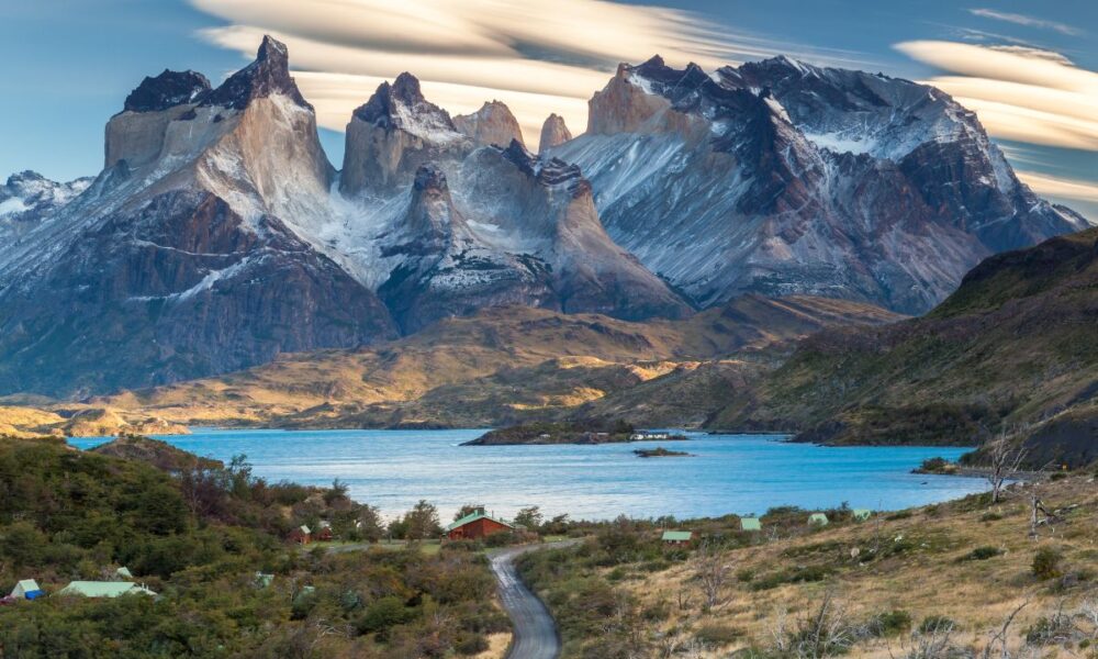 Strada che attraversa la vallata e che porta verso un lago della Patagonia cilena con sullo sfondo delle montagne rocciose con della neve