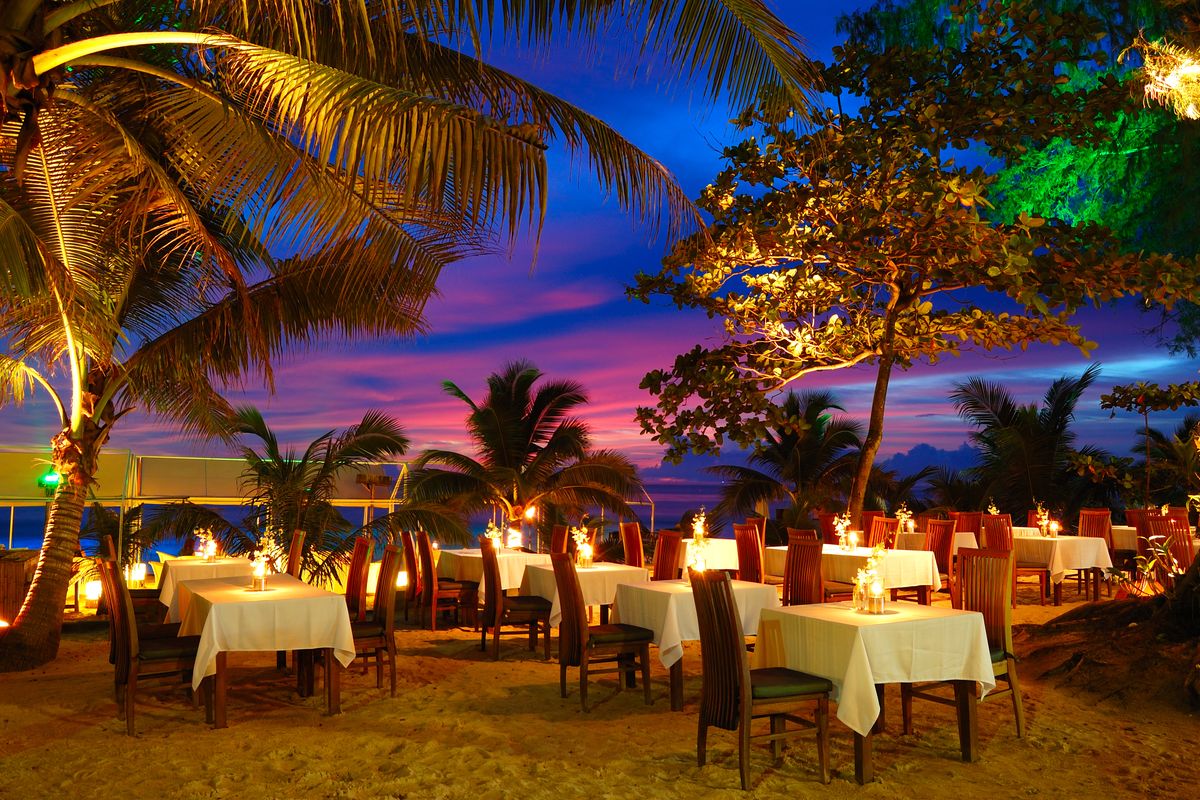 Ristorante al tramonto con tavoli sotto le palme