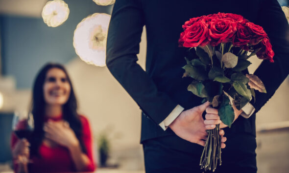 Cena di coppia con ragazzo che porta un mazzo di rose