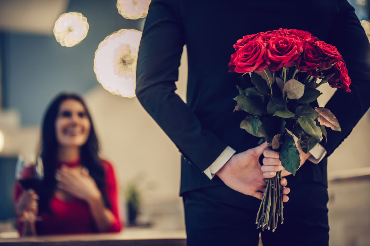 Cena di coppia con ragazzo che porta un mazzo di rose