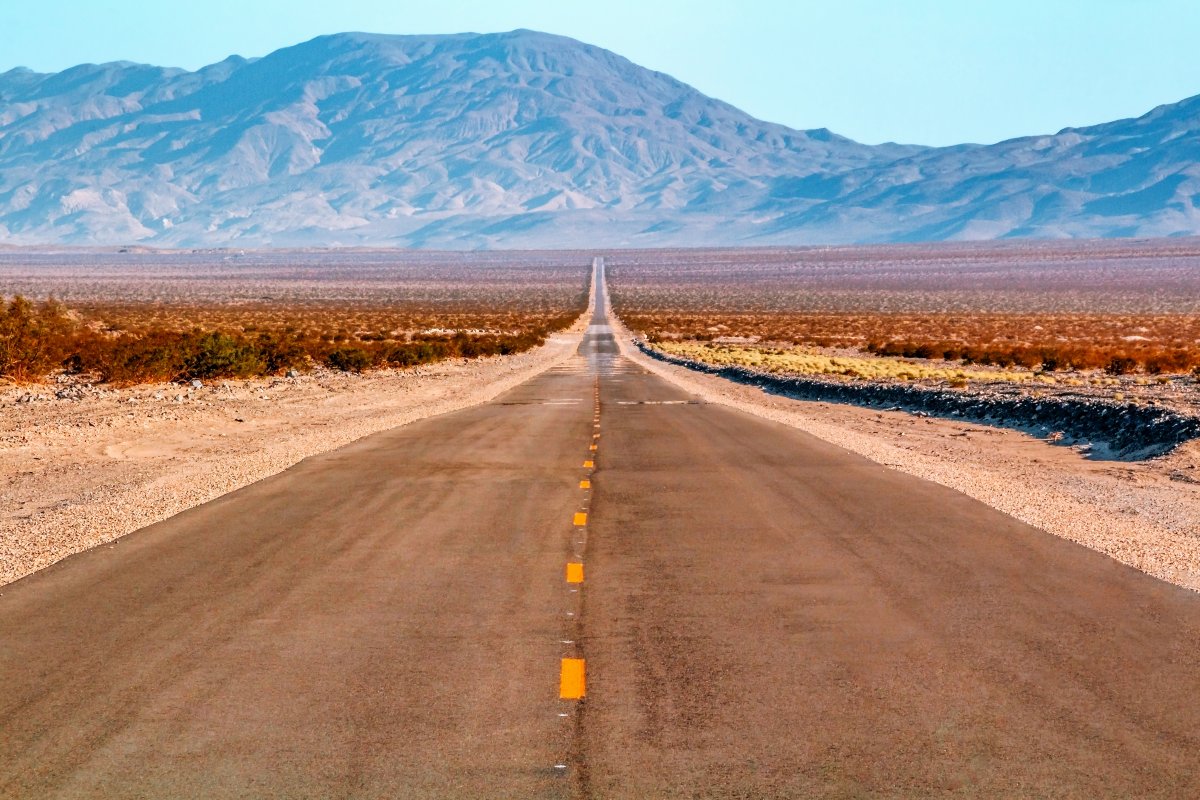 Strada che attraversa il deserto in California con sullo sfondo delle montagne