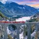 Treno che transita sul ponte Filisur in Svizzera con sullo sfondo le montagne alpine