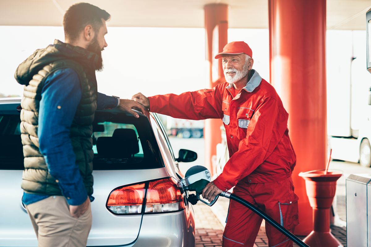 Benzinaio che fa il pieno all'auto di un guidatore