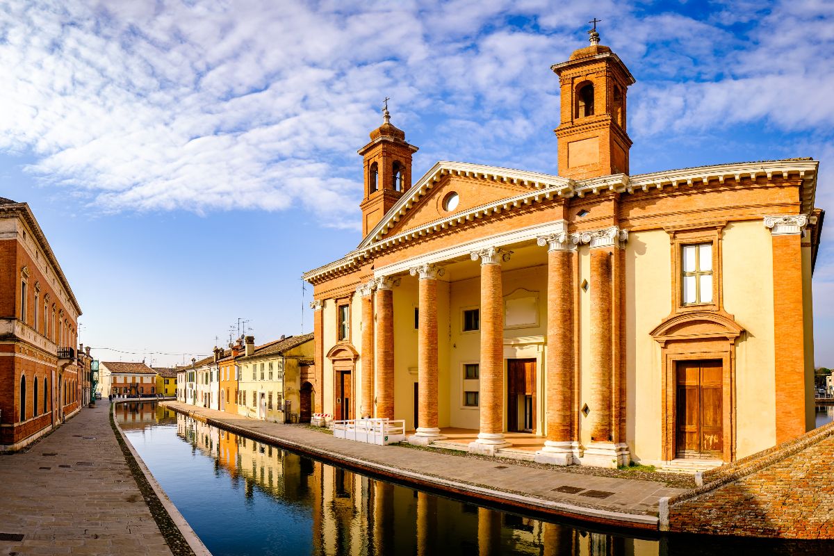 La basilica concattedrale di San Cassiano Martire, con la facciata riflessa nelle acque del canale prospicente in una giornata di sole