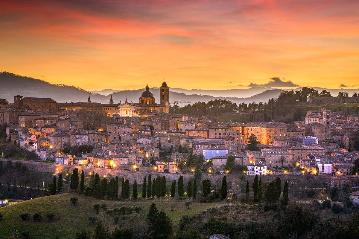 Una vista su Urbino al tramonto con il borgo illuminato