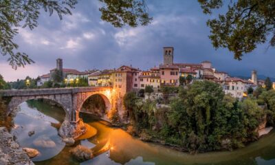 Vista di Cividale del Friuli all'imbrunire con in primo piano il fiume Natisone e il Ponte del Diavolo illuminato