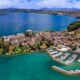 Porticciolo del Lago di Bolsena con le case del centro storico e le barche ormeggiate, con sullo sfondo il lago e la sua sponda con una piccola isola