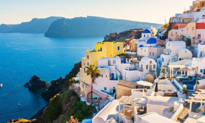 Case bianche di Santorini che si affacciano sul mare dalla parete rocciosa della costa in una giornata di sole senza nuvole