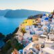 Case bianche di Santorini che si affacciano sul mare dalla parete rocciosa della costa in una giornata di sole senza nuvole