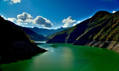Lago Ridracoli in primo piano con le sue acque verdi in una giornata di sole con qualche nube all'orizzonte