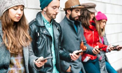 Ragazzi appoggiati al muro che guardano il loro smartphone