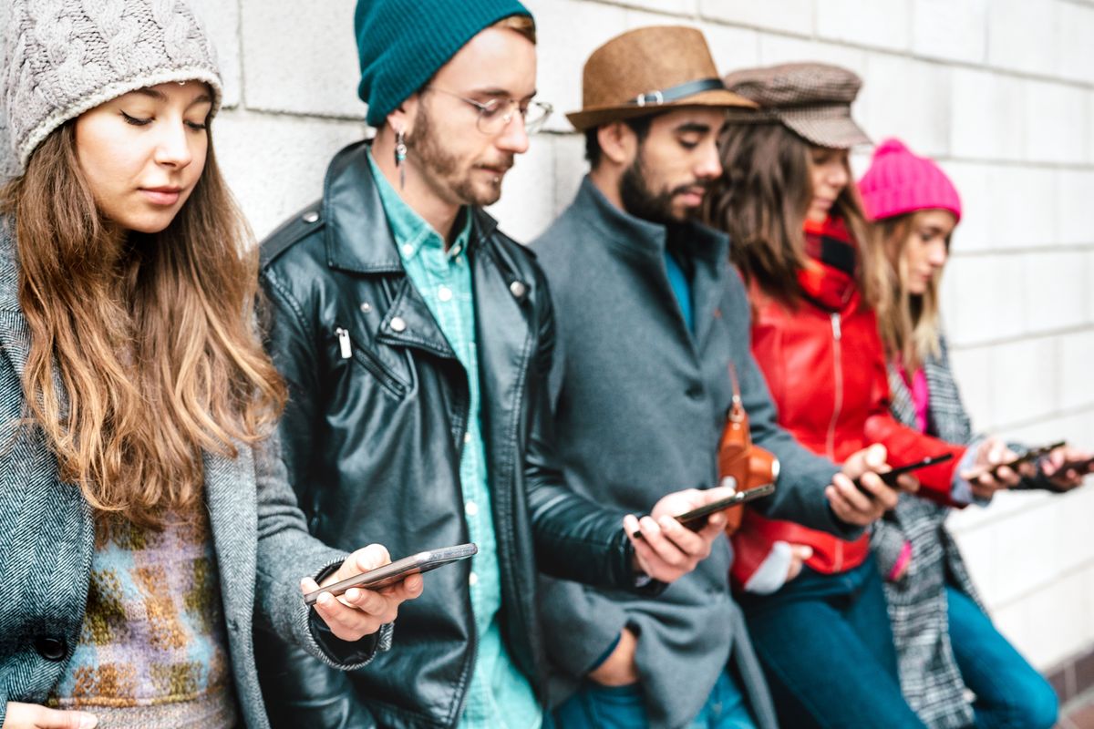 Ragazzi appoggiati al muro che guardano il loro smartphone