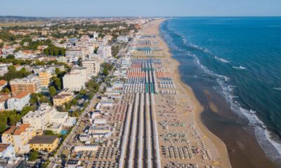 Spiaggia della Romagna con stabilimenti e file di ombrelloni con da un lato il mare e dall'altro le case del centro abitato in una giornata limpida