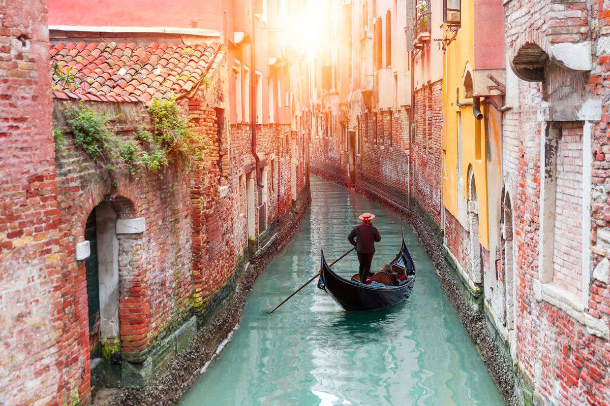 Una gondola in uno degli stretti canali di Venezia illuminato dal sole