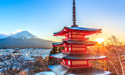Tempio rosso giapponese in primo piano che da sulla vallata con sullo sfondo il Monte Fuji innevato