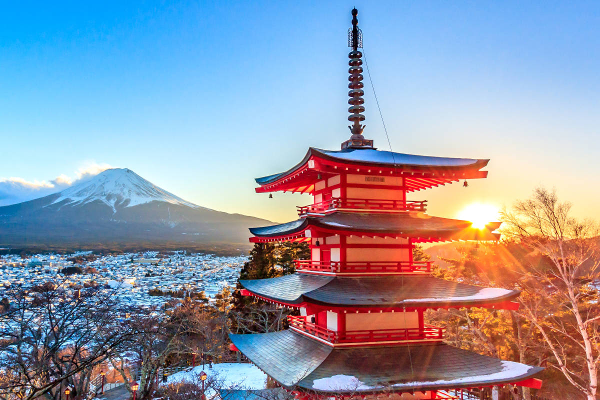 Tempio rosso giapponese in primo piano che da sulla vallata con sullo sfondo il Monte Fuji innevato