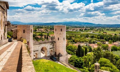 Torri delle mura di Porta Venere a Perugia con i mattoni a vista con una via laterale con porta verso il centro storico, con sullo sfondo la vallata con case e alberi e delle montagne in lontananza
