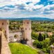 Torri delle mura di Porta Venere a Perugia con i mattoni a vista con una via laterale con porta verso il centro storico, con sullo sfondo la vallata con case e alberi e delle montagne in lontananza